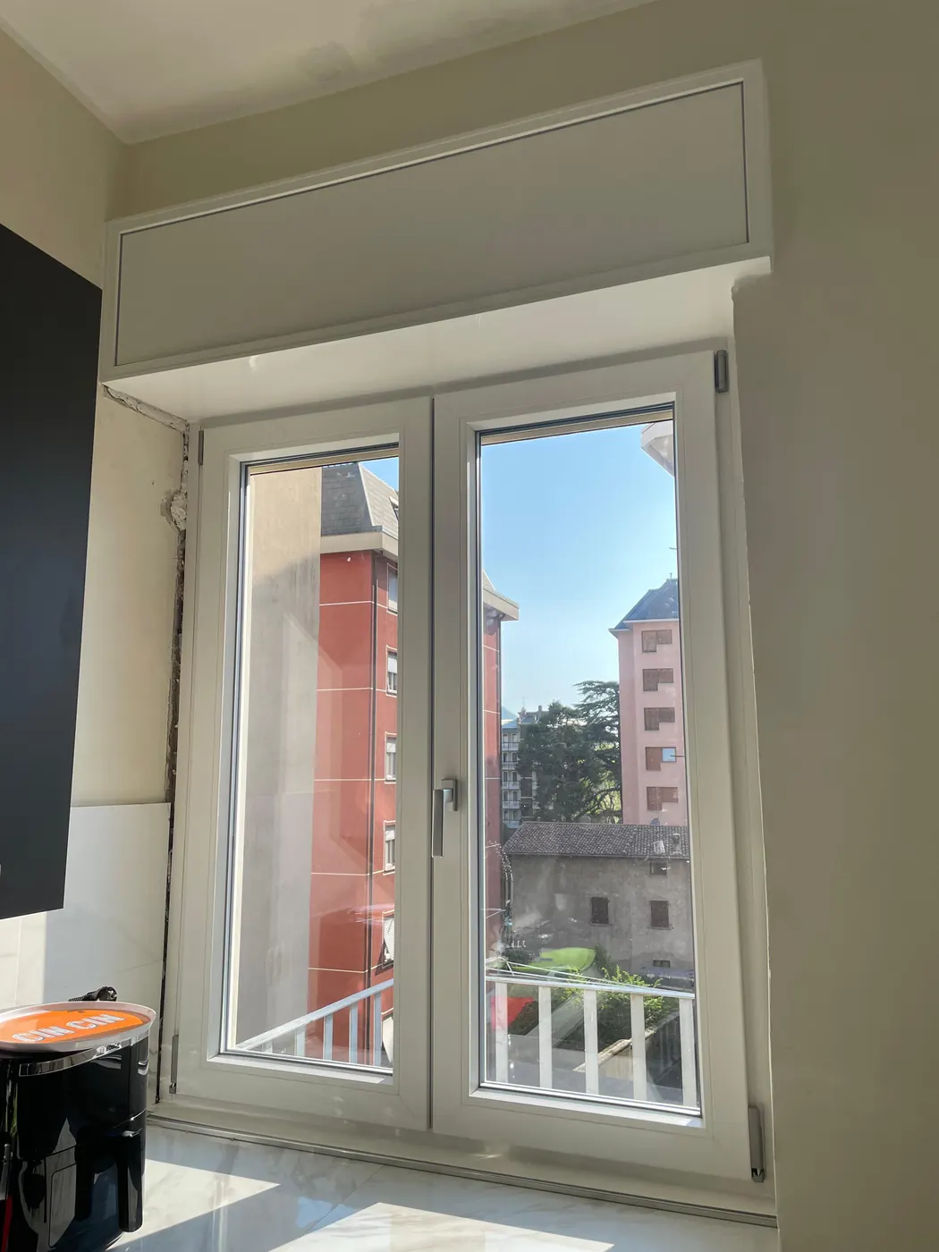 Finestra a due ante in PVC bianco posata in un soggiorno, con cassonetto nuovo
