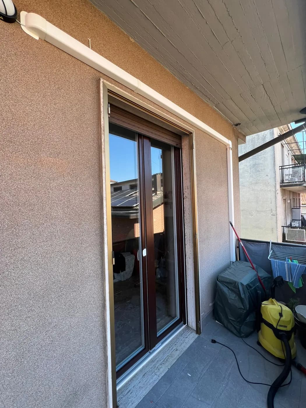 Portafinestra in tinta legno scuro verso un balcone coperto